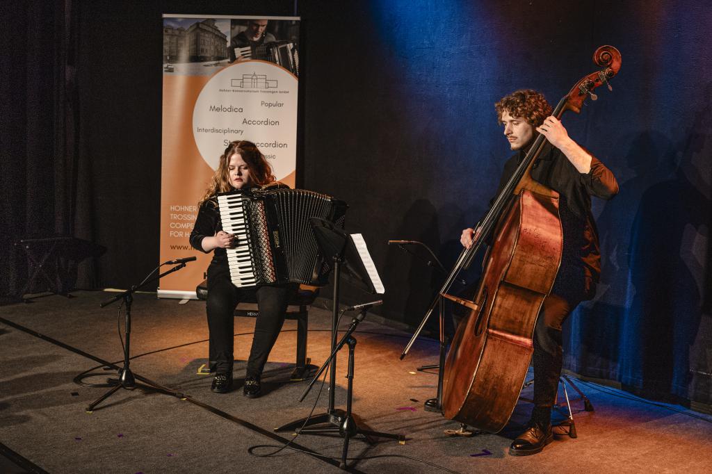 Eine Akkordeonspielende und ein Cellospieler im Rampenlicht auf der Bühne